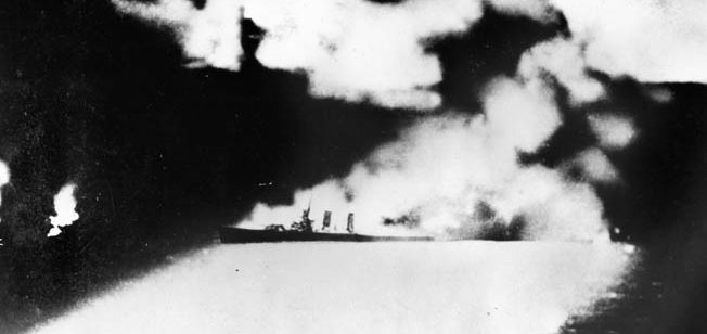 The burning cruiser USS Quincy was photographed by a Japanese cameraman at the height of the Battle of Savo Island. In this image, the doomed cruiser is illuminated by flares, searchlights, and the roaring flames that were consuming her before she plunged to the bottom.