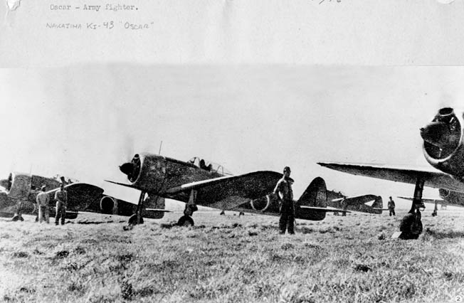 In this captured Japanese photograph, ground crewmen stand near Nakajima Ki-43 Oscar fighters being prepared for a mission. The pilots are in their cockpits and ready for takeoff. 