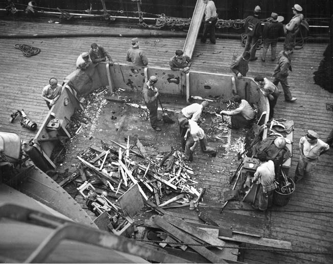 Nevada crewmen clean up damage after Japanese shore batteries on Okinawa zeroed in on her, April 1945. 