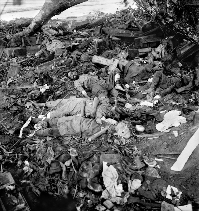 The price of aggression: A group of dead Japanese, killed during in the final Australian assault on Gona, December 17, 1942, lie in the rubble of their ammunition dump.
