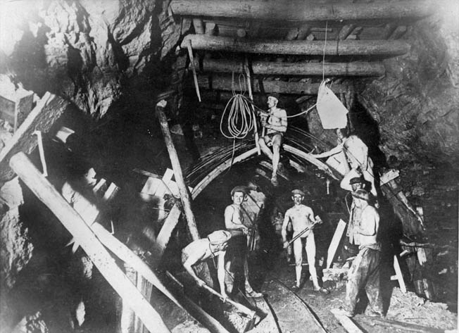 Miners chip away at coal in the warm temperatures of a mine. Nobles spent nine months working in a coal mine as a POW.