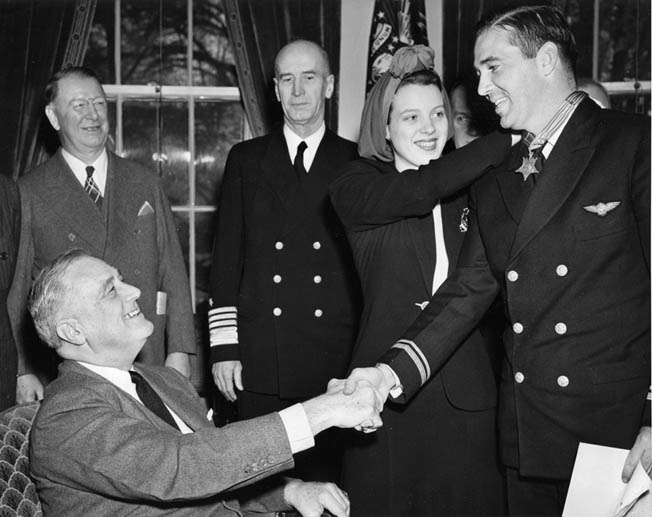 O’Hare shakes hands with President Roosevelt as his wife Rita fastens the Medal of Honor around his neck, April 21, 1942. He was promoted to the rank of lieutenant at the same time.