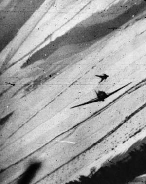 A Luftwaffe pilot hits the silk as his burning plane tumbles out of control. This still image from the gun camera footage filmed by the fighter bomber of Major James Dalglish vividly illustrates the capability of Ninth Air Force planes to perform multiple combat roles. Dalglish scored this aerial victory over Belgium during the Battle of the Bulge in late 1944. 