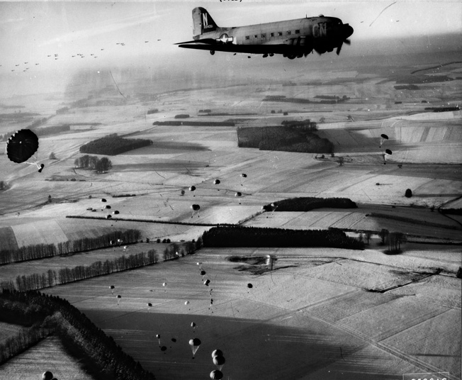 A Douglas C-47 transport aircraft of the 9th Troop Carrier Command drops vital supplies to beleaguered troops holding Bastogne during the Battle of the Bulge. This photo was taken on December 23, 1944, at the height of the German effort to capture Bastogne.