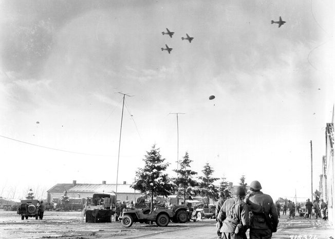 On the day after Christmas, 1944, Douglas C-47 transport aircraft drop provisions to American troops occupying Bastogne. 