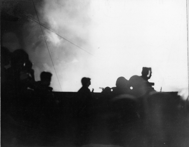 The battleship USS Pennsylvania is silhouetted against the darkened sky by the gun flashes of her cohorts on the American battle line at Surigao Strait. 