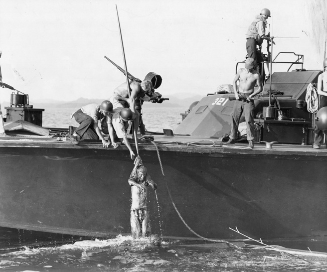 A U.S. PT Boat picks up Japanese survivors, clinging to debris in the water in Surigao Strait. The Navy seaman were warned to carefully search each prisoner to be sure they had no weapons.