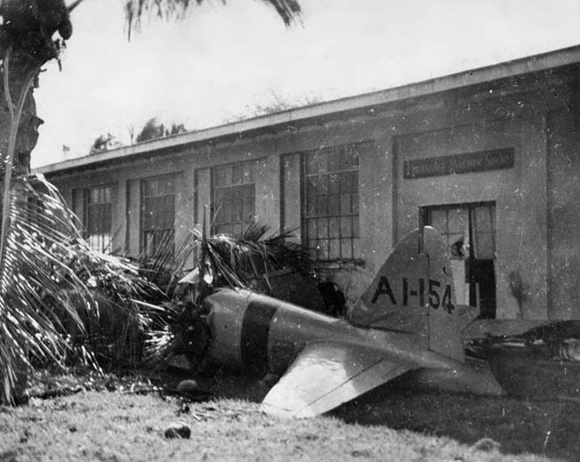 The wreckage of a Japanese Mitsubishi A6M2 Zero fighter plane lies next to a building at Fort Kamehameha on Oahu. The plane was hit by American fire and crashed while attempting to strafe installations on the ground. 