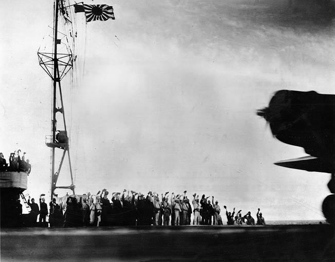 Japanese crewmen aboard the aircraft carrier Shokaku cheer as a Nakajima B5N2 “Kate” torpedo bomber takes off for Pearl Harbor at about 7:00 am.