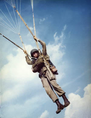 A British paratrooper carries his gear off the landing zone after a  re-enactment of a World War II parachute jump on the 40th anniversary of  D-day, the invasion of Europe - PICRYL 