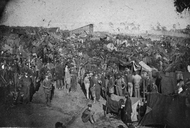 Starving Union prisoners wait at the main gate at Andersonville for their meager rations to be issued.
