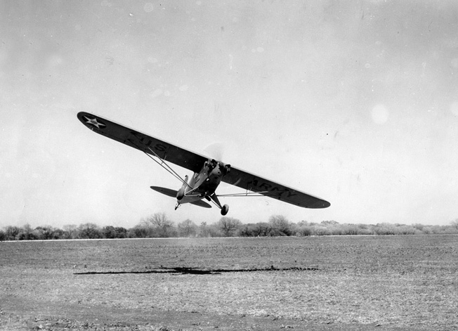 Not requiring a hard runway, an L-4 lands in a field.