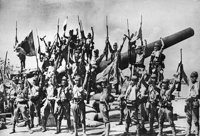 Japanese soldiers pose for a victory photo on the island of Corregidor, Philippines, May 6, 1942. The soldiers are gathered around a 12-inch M1895A2 gun at Battery Hearn. 