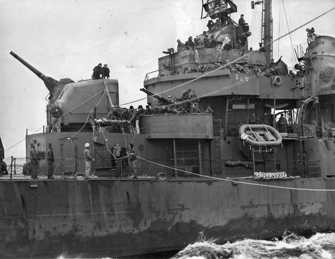 A photographer aboard the destroyer USS Hunt (DD-674) captures the transfer of an injured Franklin survivor—one of 429 she picked up—to the battlecruiser USS Alaska. The Alaska then shepherded the Franklin to a port on Guam.