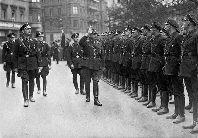 SA (Sturmabteilung) commander Ernst Röhm, with Himmler trailing, reviews a formation of SS troops in Berlin shortly before the SA chief’s assassination in 1933. At this time, the SS was still subservient to the SA. 