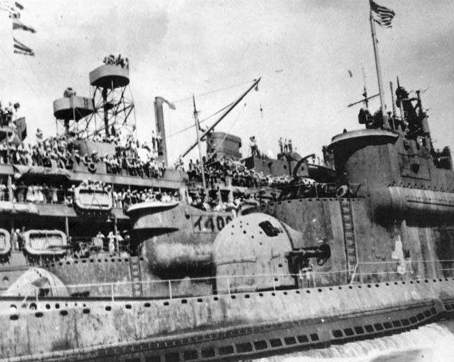 Sailors aboard the submarine tender USS Proteus (background) line the rails to view the I-400 and I-401 in Tokyo Bay, September 1945. The large rounded structure in the center of the photo is I-401’s outer access door to the hangar.