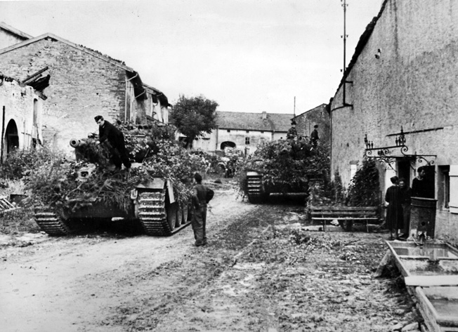 Trying to make their tanks and other vehicles inconspicuous to American aircraft, German troops cover them with tree branches in a town near the Moselle River.