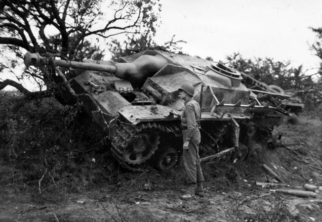 A GI examines a knocked-out StuG IV near Lunéville, France. The StuG IV had no rotatable turret; the entire vehicle had to be aimed in the direction of the target.