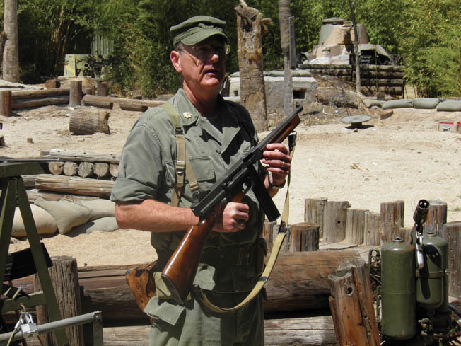 Richard Koone, education director of the museum, gives a weapons demonstration in front of the realistic “Tarawa” battlefield at the Pacific Combat Zone. 