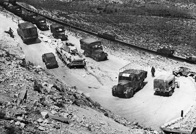 A convoy of German supply vehicles climbs a mountain road to Derna, passing a wrecked German tank, May 1941. As the campaign wore on, Axis vehicles fell victim to growing Allied air superiority.