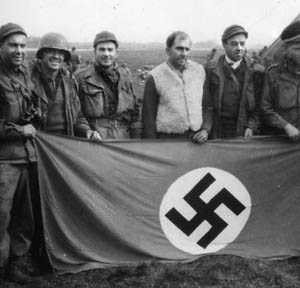 The spoils of war. Flight Officer Tom Warner (third from left) and some buddies pose with a captured Nazi flag “somewhere in Germany.”