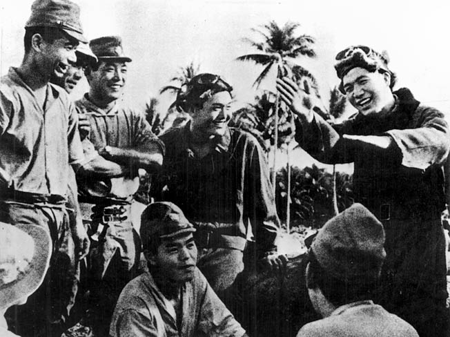 A happy Japanese pilot (right) demonstrates to his comrades some of the aerial combat moves he made against the Marine aviators.