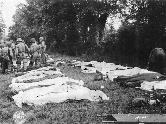 Dead American paratroopers are gathered in a field by a Graves Registration unit prior to burial.