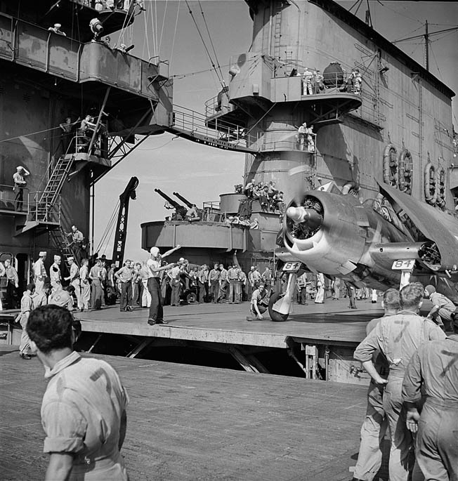 A carrier’s flight-deck crew watches carefully as an officer guides a Hellcat toward the elevator, which is being raised into position, November 1943. Each plane was assigned a captain who was responsible for staying with that particular plane. Pilots, however, did not fly the same plane.