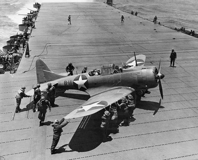 Flight-deck crew on the USS Hornet pushes an SBD of Bombing Squadron VB-8 into position for takeoff during the Battle of Midway, June 2, 1942. 