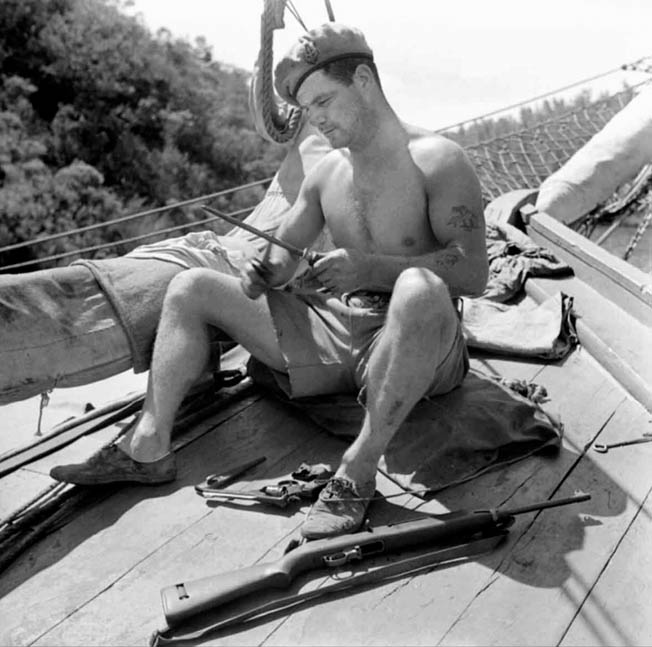 An SBS corporal sharpens his fighting knife prior to a mission. 