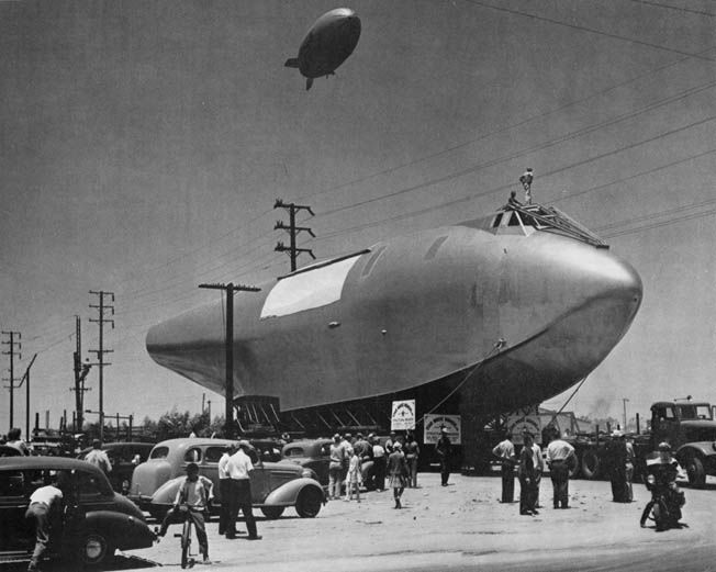 Power lines needed to be removed for the fuselage’s 28-mile journey in June 1946 from the Hughes Aircraft Company factory in Culver City to Pier E in Long Beach for final assembly. A blimp overhead follows the progress.