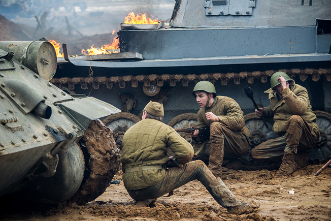 Russian reenactors take cover behind a T-34 tank (left) and a 'knocked out' mock Panzer (right) as they storm the model Reichstag at Patriot Park. Photo Credit: Ministry of Defense of the Russian Federation.