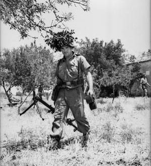 With his helmet well camouflaged, a Hermann Göring Division paratrooper moves to take up a defensive position with his 7.92mm MG 15. The weapon, originally used as an aircraft gun, had a rate of fire of over 1,000 rounds per minute. 