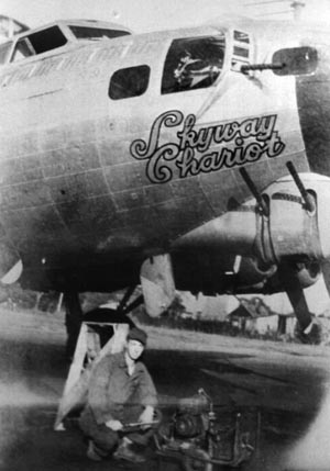 A ground crewman poses under the nose of Skyway Chariot with a “putt-putt” used to start engines.