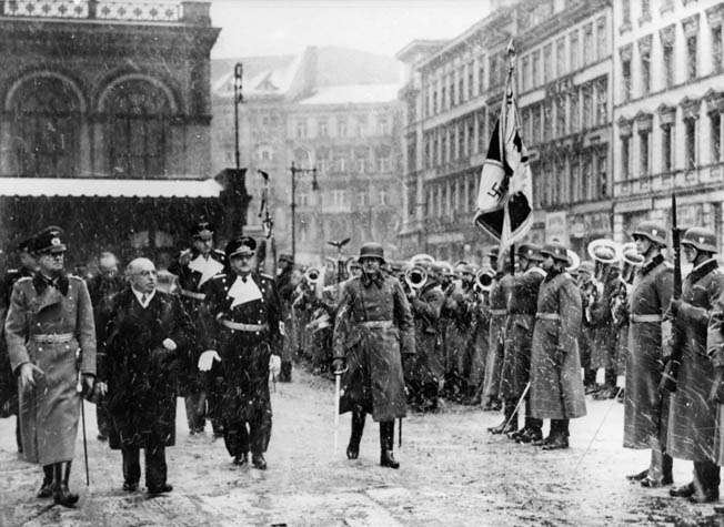 Dr. Emil Hacha, president of Czechoslovakia, is escorted past an honor guard while on his way to a meeting with Adolf Hitler where he signed away the independence of the Czech nation in March 1939.