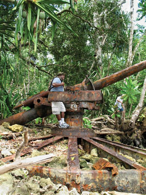 Although covered by a patina of rust, this 6-inch Japanese coastal defense gun, one of four guns at Enogai inlet on New Georgia Island, still looks lethal. Posing on the gun is Ken White, a Navy Corpsman Reservist and OR technician working with the Loloma Foundation.