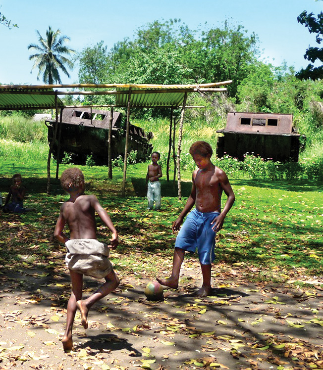 Two of over 70 amtraks left near Red Beach in Tetere appear to stand guard as Solomon Island children play soccer.