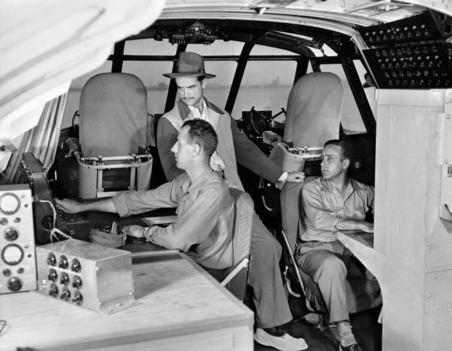 Hughes watches engineer Chal Bowen, October 31, 1947, two days before the flight as the radio operator looks on. Thirty-six people were on board for the test flight.