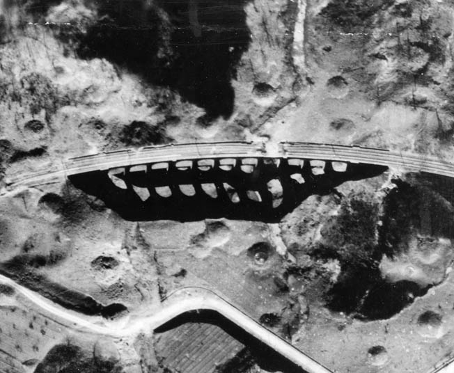 Bomb damage to the South Viaduct at Bucine, Italy, after several attacks by B-26s of the 442nd Bomb Squadron, 320th Bomb Group, Fifteenth Air Force, in April 1944. Bomb craters surround the bridge. 