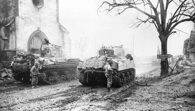Seventh Army troops advance through a French village behind two M-4 Sherman tanks. Sparks used tanks to his advantage while rescuing his troops north of Reipertswiller, January 1945.