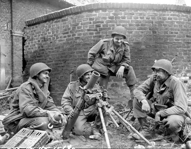 A 104th Division mortar crew smiles as they pose around a captured German 81mm mortar they used against the enemy near Duren, Germany.