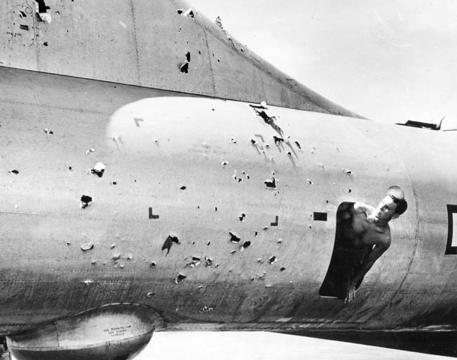 A crew member surveys the damage to his B-29 caused by Japanese flak guns during an April 1945 raid on the Japanese capital.