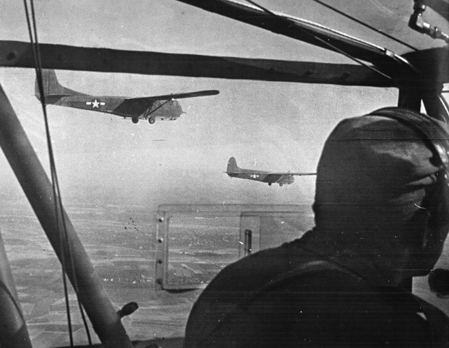 Waco CG-4A gliders carrying troops of the 17th Airborne Division fly over Wesel, Germany, in a new, double-tow formation the morning of March 24. 