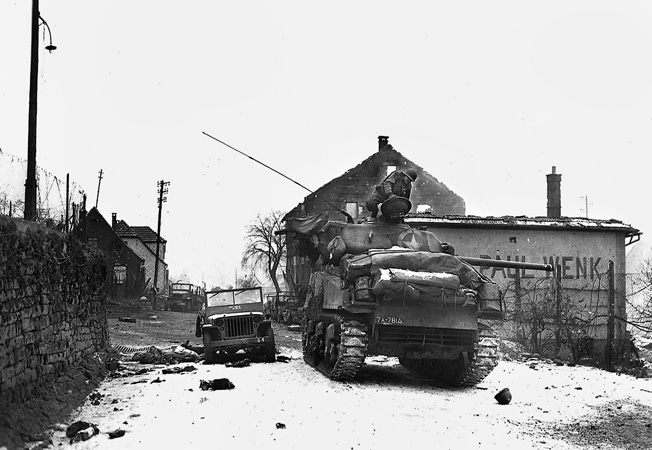 An M4 Sherman tank of the 781st Tank Battalion, in support of the 100th Division outside of Wingen-sur-Moder, France, January 6, 1945. A GI helmet and knocked-out vehicles bear witness to the fierce fighting.