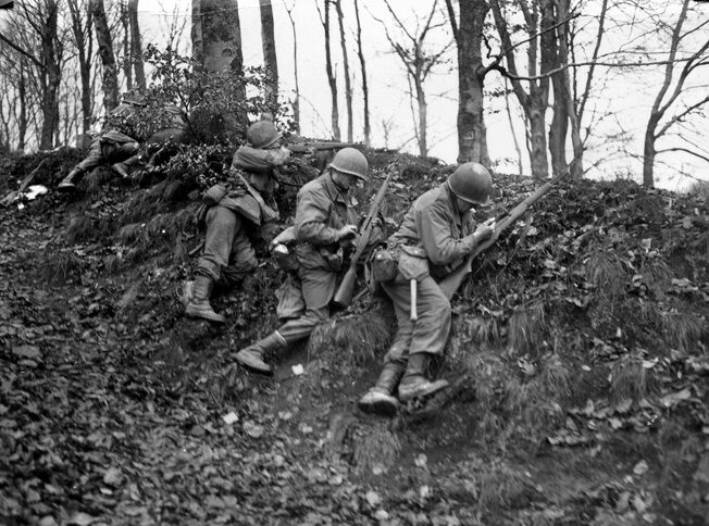 100th Infantry Division riflemen fire from behind a berm near Rosteig, France, several miles south of Lemberg, in early December 1944.