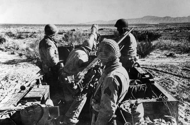 American soldiers prepare to load and fire a half-track-mounted artillery piece during the North African campaign. 