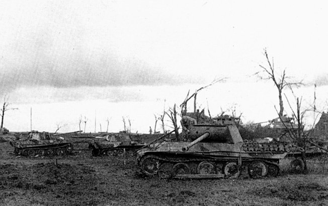 Mute testimony to the bitter fighting that took place near Guebling, France, the battered hulks of four German tanks and tow american tanks lie derelict on the field.