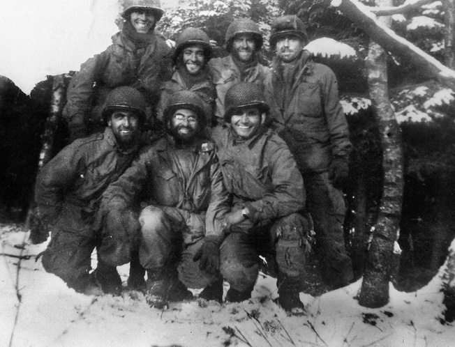 Glider infantryman Carmen Gisi, kneeling in the center of this photo, took possession of a camera lost at a shattered field hospital and took numerous photos around the operations area of Company B, 1/401st Glider Infantry Regiment near Crossroads X.