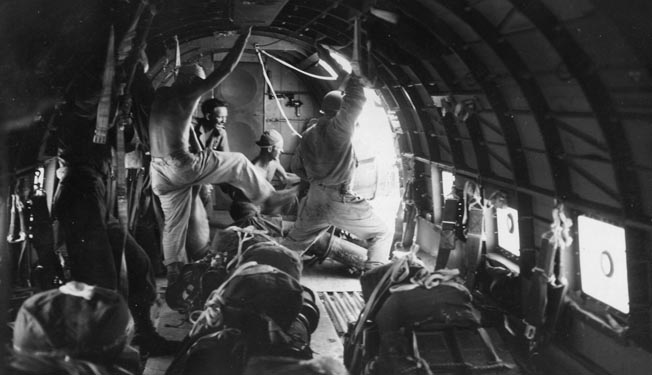 An American airman kicks a packet of supplies out the cargo door of a transport aircraft during the 38th Division offensive on the Bataan Peninsula. The difficult terrain required resupply by air, particularly during the struggle for control of Zig Zag Pass.