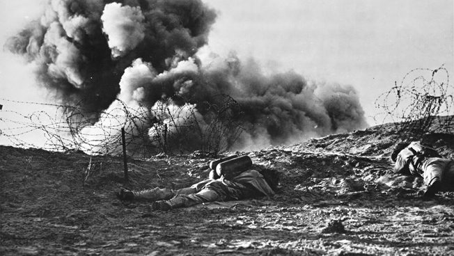 During training exercises in Britain, American soldiers blast barbedwire entanglements with a Bangalore torpedo, an explosive that was supplied to the troops in tubular sections and assembled on the beach. One soldier is conspicuous with the fuel tanks of his flamethrower visible. 